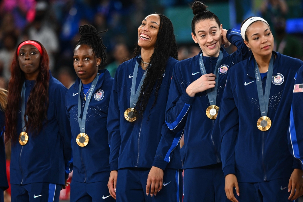 Gold medallists (From L) USA's #07 Kahleah Copper, USA's #08 Chelsea Gray, USA's #09 A'ja Wilson, USA's #10 Breanna Stewart and USA's #11 Napheesa Collier pose with their medal on the podium after the women's Gold Medal basketball match between France and the USA during the Paris 2024 Olympic Games at the Bercy Arena in Paris on August 11, 2024. (Photo by Aris MESSINIS / AFP)
