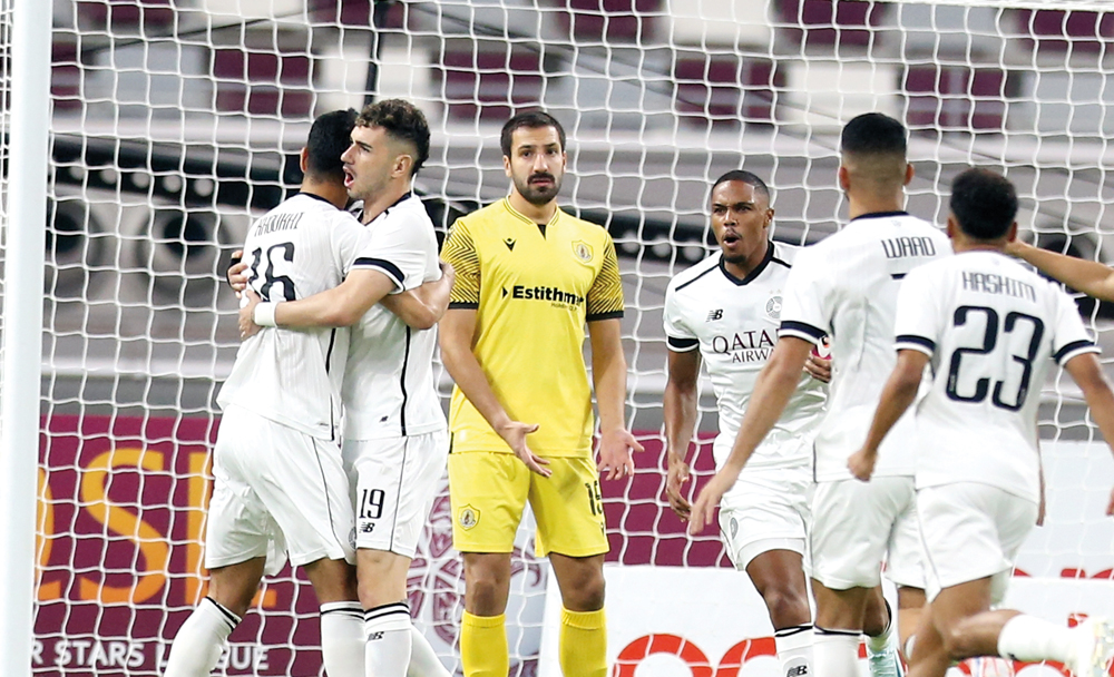 Al Sadd's Rafa Mujica (second left) celebrates with teammate Boualem Khoukhi after scoring a goal against Qatar SC. 
