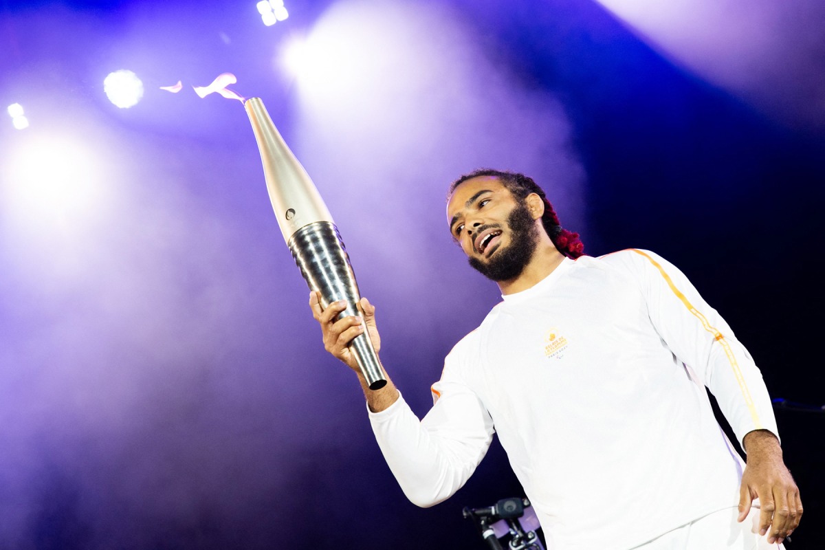 French paralympic athlete Helios Latchoumanaya holds the Paralympics flame during the 20th edition of the Rock en Seine music festival, in Saint-Cloud, outside Paris.