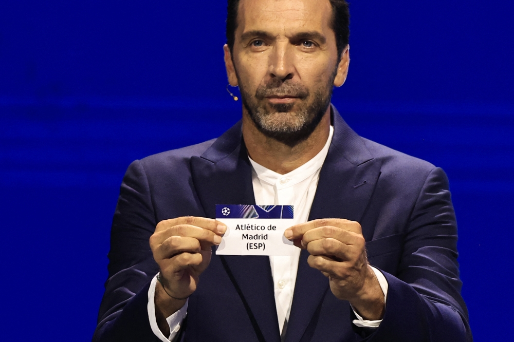 Italy's former goalkeeper Gianluigi Buffon shows the paper slip of Atletico Madrid (ESP) during the group stage of the 2024-2025 UEFA Champions League football tournament, at the Grimaldi Forum in Monaco on August 29, 2024. (Photo by Valery Hache / AFP)