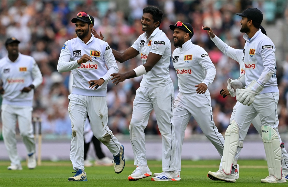 Sri Lanka's Dimuth Karunaratne (L) celebrates with teammates after taking the wicket of England's captain Ollie Pope (unseen) on day two of the thrid cricket test match between England and Sri Lanka on September 7, 2024. (Photo by Glyn KIRK / AFP)