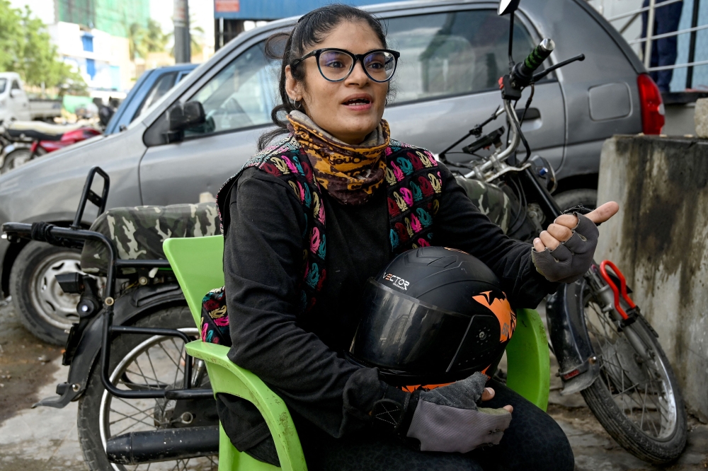 In this photograph taken on August 19, 2024, Amina Sohail, a motorbike rider with a local ride-hailing service provider Bykea, speaks during an interview with AFP in Karachi. (Photo by Rizwan Tabassum / AFP) 