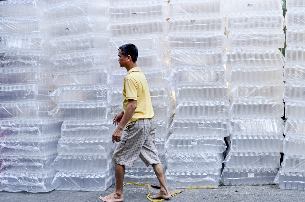 A man walks past plastic bottles on a street in Hanoi on September 16, 2024. (Photo by Nhac NGUYEN / AFP)