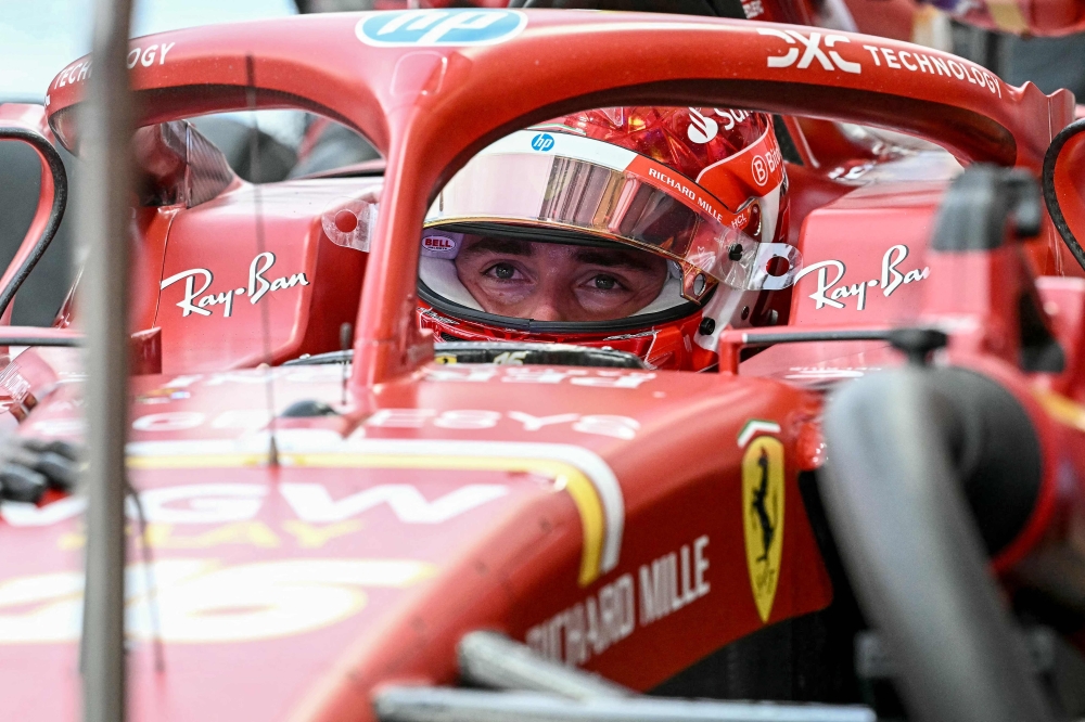 Ferrari's Monegasque driver Charles Leclerc looks on as team mechanics work on his car during the first practice session ahead of the Formula One Singapore Grand Prix night race at the Marina Bay Street Circuit in Singapore on September 20, 2024. (Photo by Lillian SUWANRUMPHA / AFP)