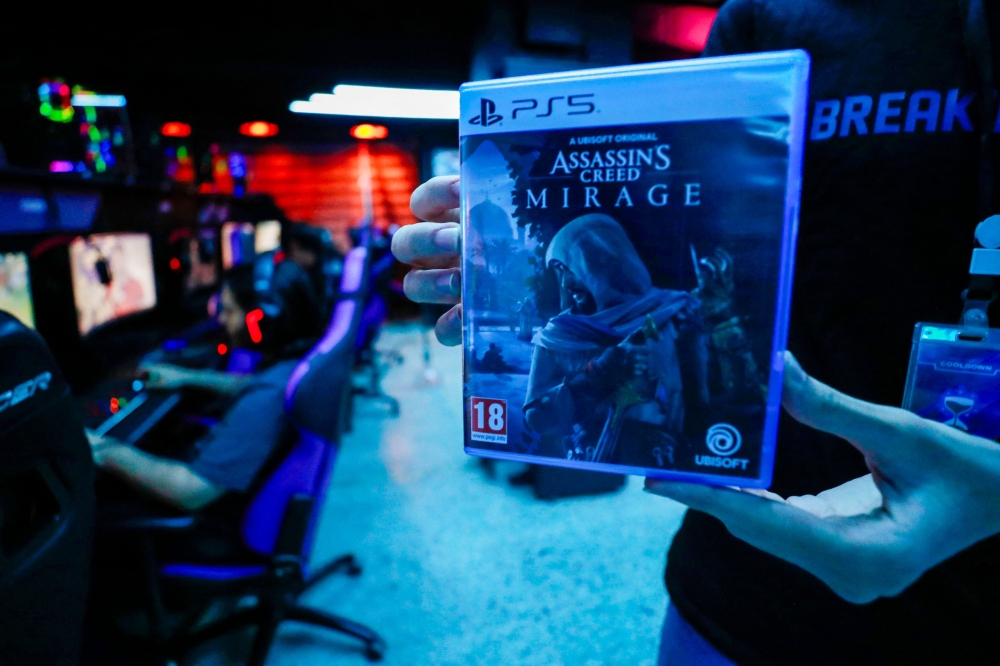 An employee shows a copy of the newly released video game 'Assassin's Creed Mirage' in their cybercafe in Baghdad on October 4, 2023. (Photo by Ahmad AL-RUBAYE / AFP)

