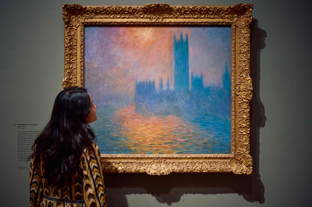 A gallery assistant studies a work by the french impressionist painter Claude Monet, 