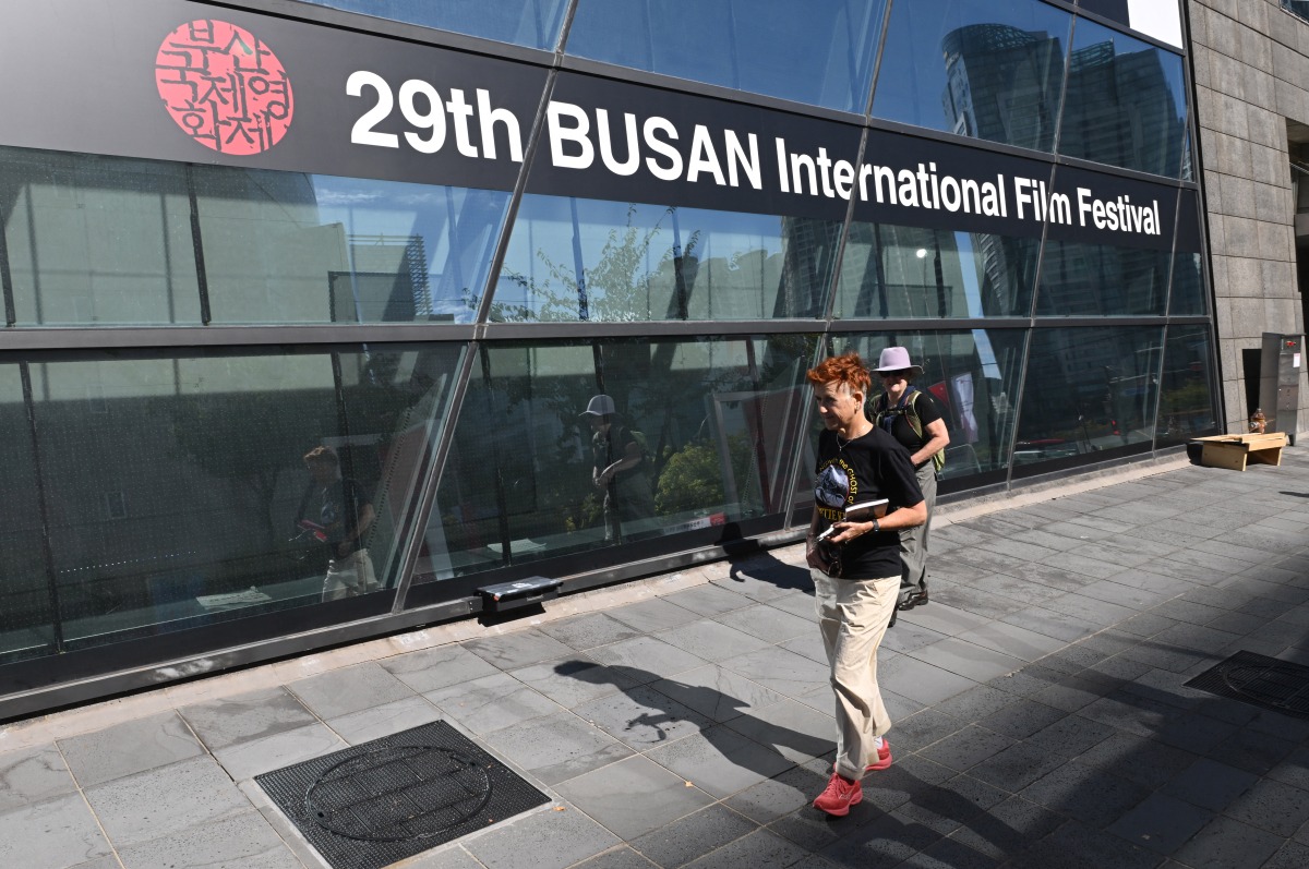 Pedestrians walk past past a banner for the 29th Busan International Film Festival (BIFF) at the Busan Cinema Center in Busan on October 2, 2024. (Photo by Jung Yeon-je / AFP)