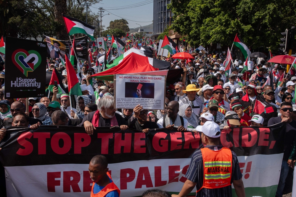 Protestors hold banners and wave Palestinian flags as they take part in a pro-Palestinian march in Cape Town, on October 05, 2024. (Photo by Rodger Bosch / AFP)