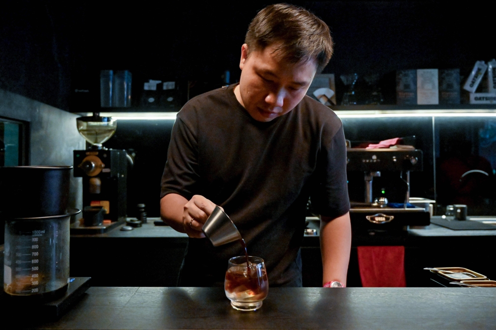 This photo taken on September 30, 2024 shows coffee house owner Vu Dinh Tu making coffee at a cafe in Hanoi. Photo by Nhac NGUYEN / AFP