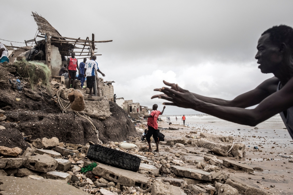 A man repairs his makeshift protection wall, to protect his house before the next high tide arrives in Bargny on September 03, 2020. Photo by JOHN WESSELS / AFP