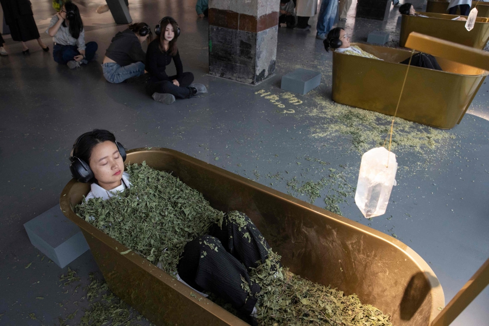 Visitors submerge themselves in tubs filled with dried leaves, as part of an interactive artwork by Serbian conceptual artist Marina Abramovic on October 11, 2024. (Photo by AFP) 