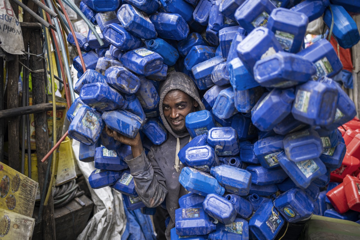 Ezedin Muste moves a huge pile of plastic soap containers at the historical Merkato district of Addis Ababa on October 1, 2024. (Photo by Michele Spatari / AFP)