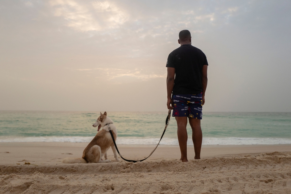 Ahmed brings his dog Rogue, a Siberian husky dog, for a walk at the beach of Nouakchott, on September 28, 2024. Photo by MICHELE CATTANI / AFP