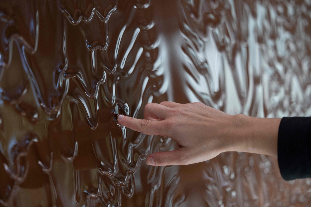 A woman puts her finger in chocolate waterfall at the entrance to the E. Wedel Chocolate Factory museum in Warsaw, Poland on October 10, 2024. Photo by Wojtek RADWANSKI / AFP