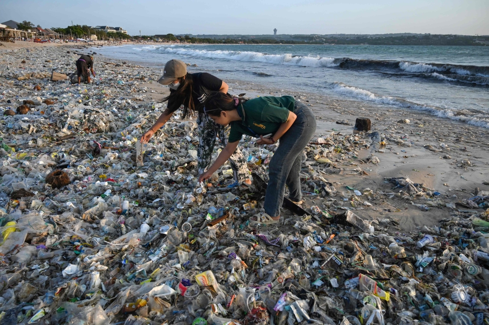 (Files) People look through plastic and other debris washed ashore at Kedonganan Beach near Denpasar on Indonesia's resort island of Bali on March 19, 2024. (Photo by Sonny Tumbelaka / AFP)
 