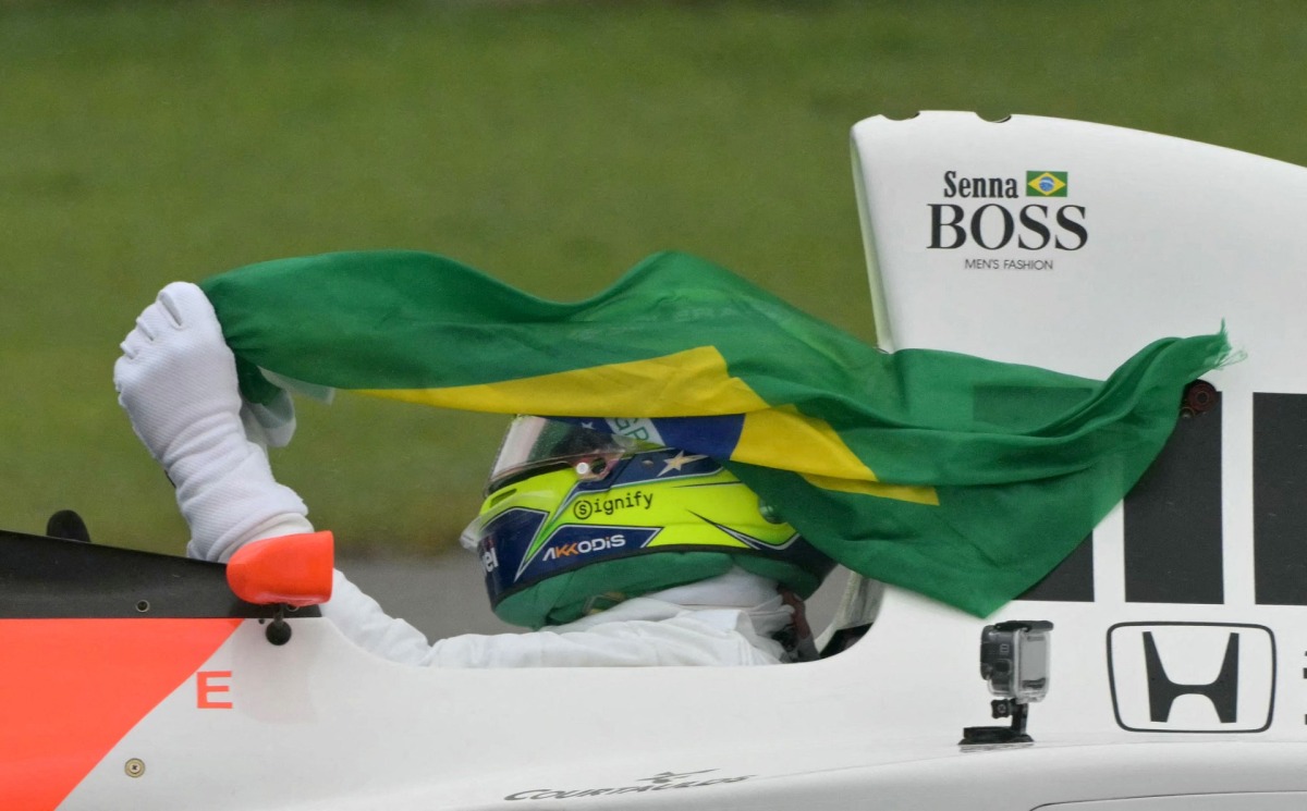 Mercedes' British driver Lewis Hamilton holds a Brazilian flag while driving the McLaren MP4-5B with which the late Ayrton Senna won his second Formula 1 world title in 1990 during a lap to mark the 30th anniversary of Senna's death at the San Marino Grand Prix, ahead of the Formula One Sao Paulo Grand Prix at the Jose Carlos Pace racetrack, aka Interlagos, in Sao Paulo, Brazil, on November 3, 2024. Photo by NELSON ALMEIDA / AFP.