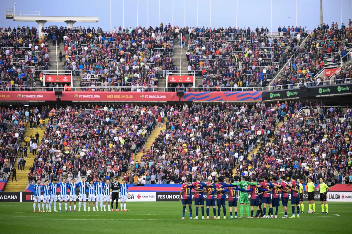 Both teams' players observe a minute of silence for the flood victims in the Valencia region before the the Spanish league football match between FC Barcelona and RCD Espanyol at the Estadi Olimpic Lluis Companys in Barcelona, on November 3, 2024. (Photo by Josep LAGO / AFP)
