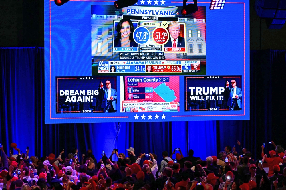 Supporters of former US President and Republican presidential candidate Donald Trump take pictures of a screen during an election night event at the West Palm Beach Convention Center in West Palm Beach, Florida, early on November 6, 2024. (Photo by Jim Watson / AFP)
 