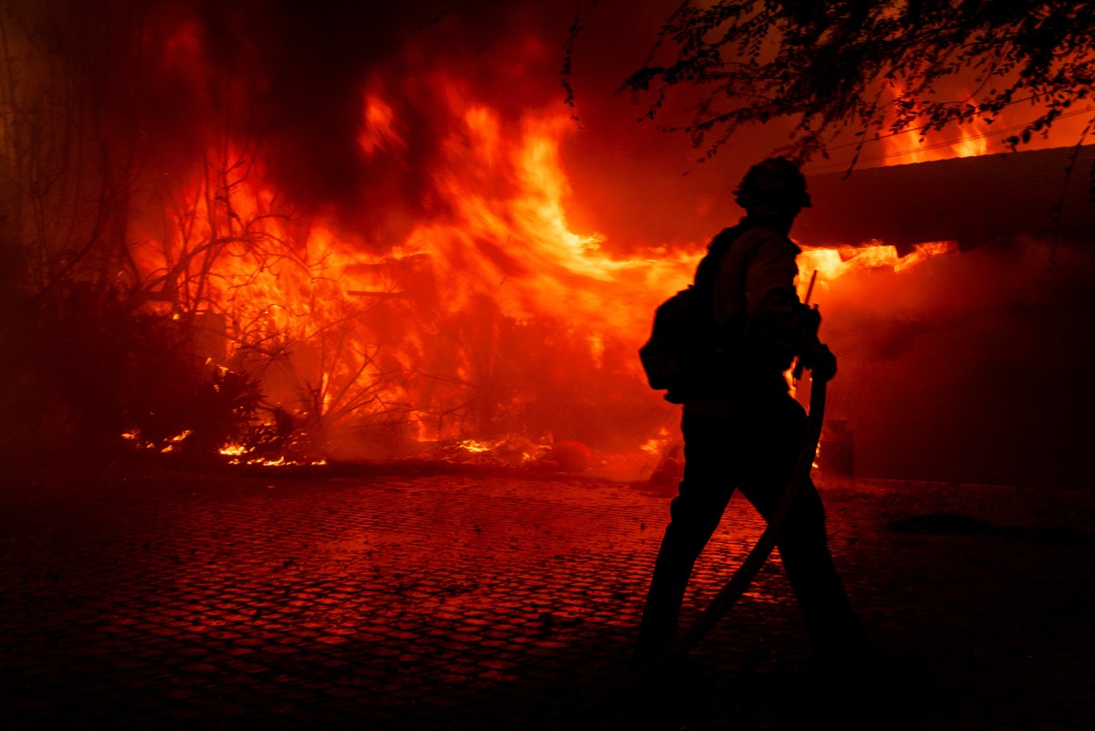 A firefighter tries to control the fire burning down a house as the Mountain Fire scorches acres, the wildfire fueled by strong Santa Ana winds, in Camarillo, California, on November 6, 2024. Photo by ETIENNE LAURENT / AFP