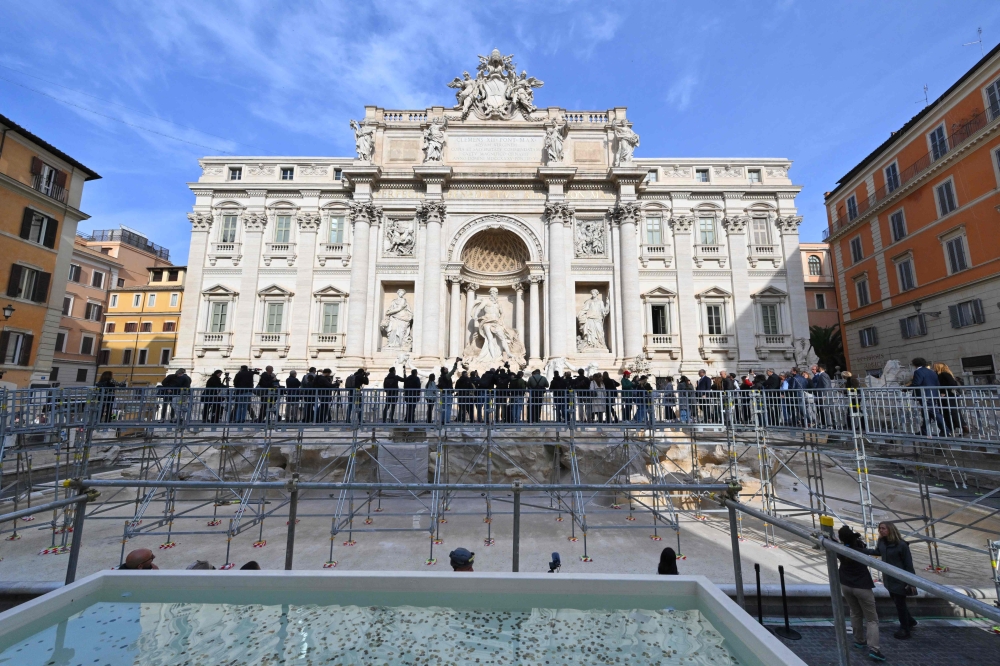 People walk on the temporary suspended walkway opening today at Trevi Fountain allowing visitors to see the fountain closer during renovation works, in Rome, on November 9, 2024. (Photo by Andreas Solaro / AFP)