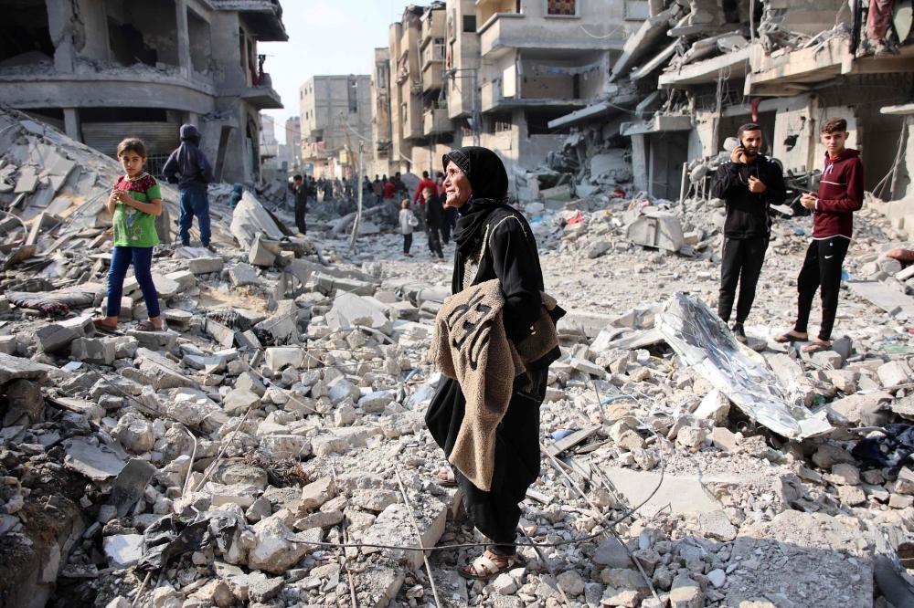 Palestinians walk amid the destruction following an Israeli strike in Jabalia in the northern Gaza Strip on November 10, 2024. (Photo by Omar Al-Qattaa / AFP)

