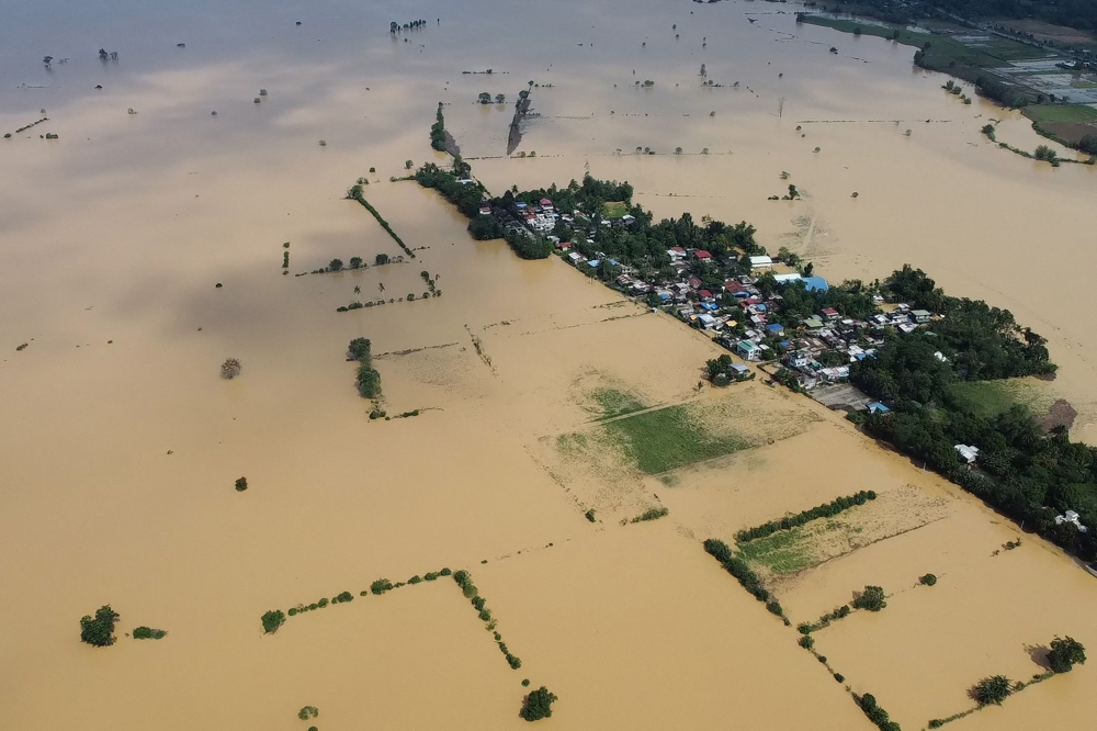 An aerial photo shows a swollen river inundating farm fields and houses at a village in Ilagan town, Isabela province on November 12, 2024, a day after Typhoon Toraji hit the province. (Photo by Villamor Visaya / AFP)