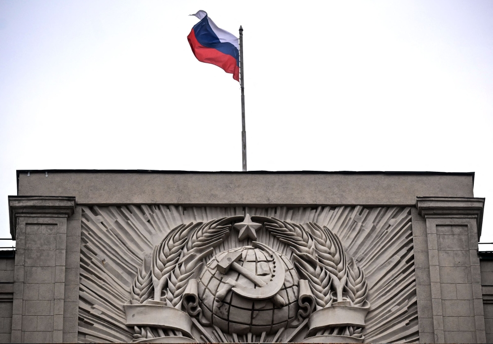 File: A Russian national flag flies atop the Russian State Duma, lower house of Russia's Parliament, as the State Emblem of the Soviet Union is seen on the Soviet era facade, in central Moscow on July 14, 2023.  (Photo by Natalia Kolesnikova / AFP)