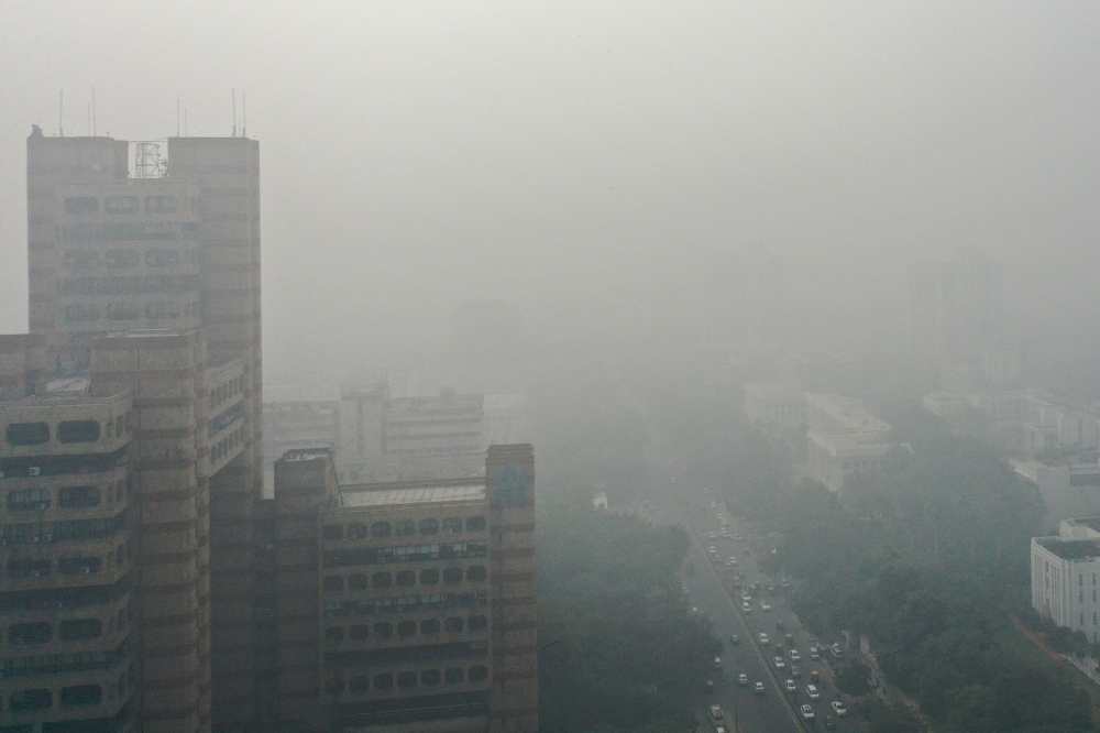 An aerial view shows cars along a road engulfed in smog in New Delhi on November 13, 2024. (Photo by Arun Sankar / AFP)
