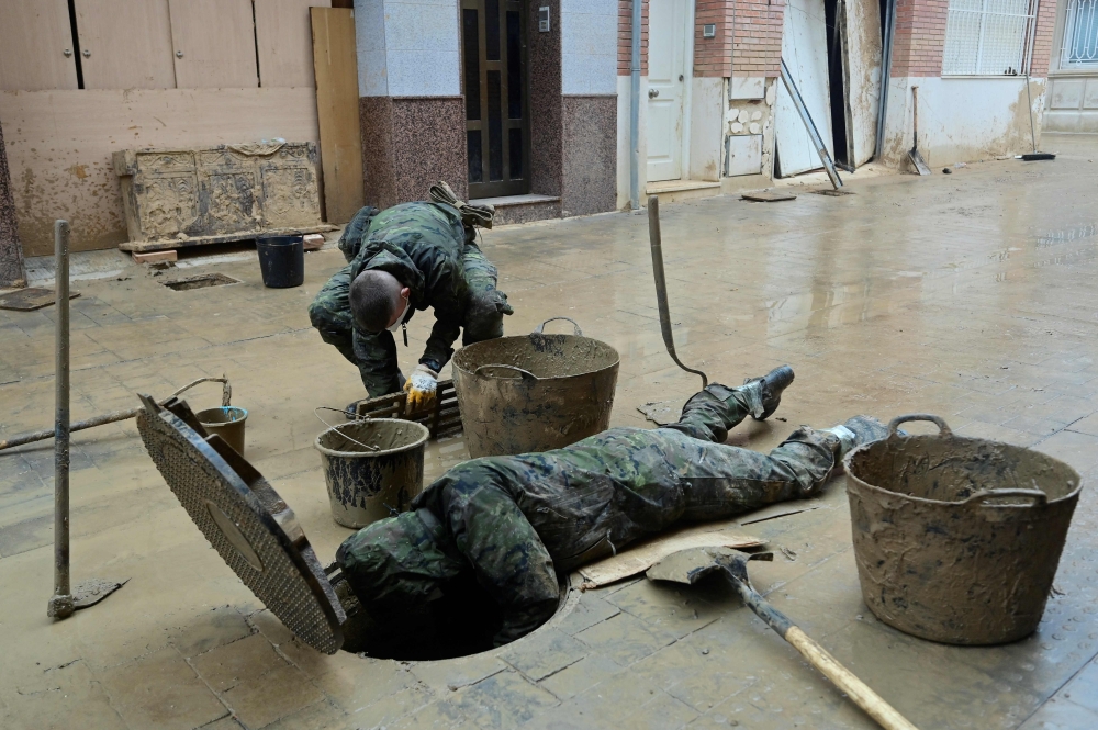 Soldiers evacuate mud from a sewer in Paiporta, south of Valencia, eastern Spain, on November 13, 2024 in the aftermath of deadly flooding. (Photo by Jose Jordan / AFP)