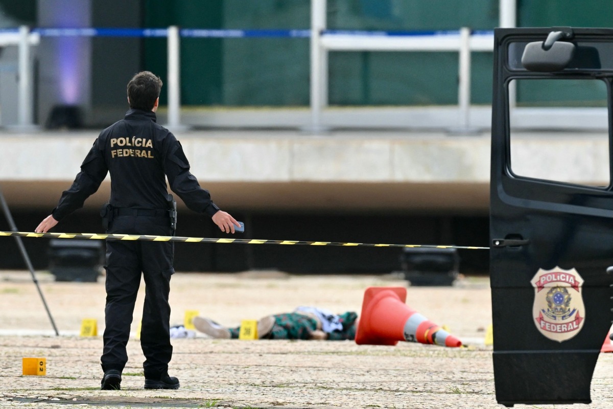 A Brazilian Federal Police stands on November 14, 2024 nearthe body of man carrying explosives who died in a blast as he attempted to attack Brazil's Supreme Court in Brasilia on November 13. (Photo by EVARISTO SA / AFP)