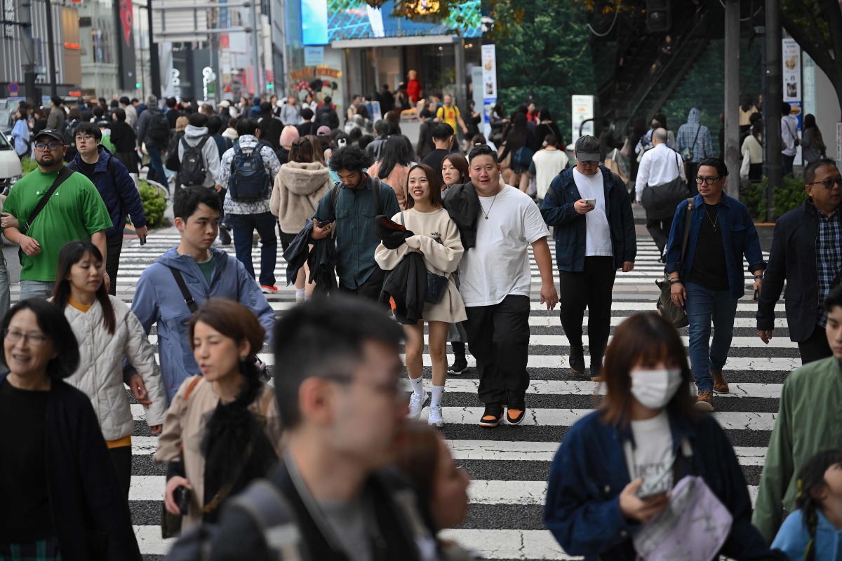 People cross a street in the Omotesando shopping area in Tokyo on November 15, 2024. (Photo by Yuichi YAMAZAKI / AFP)