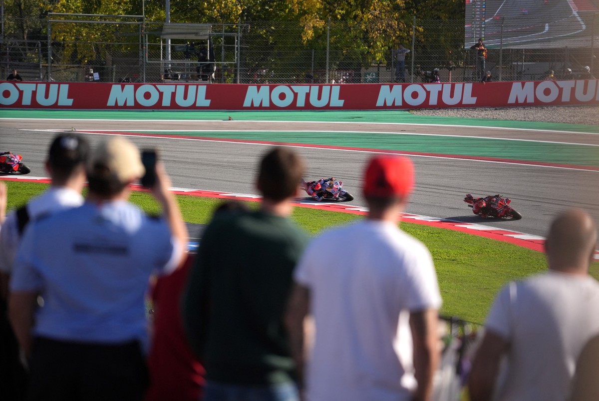 Photo used for demonstration purposes. Spectators watch as Ducati Italian rider Francesco Bagnaia (R) followed by Ducati Spanish rider Marc Marquez and Ducati Spanish rider Jorge Martin (L) compete during the MotoGP Solidarity Grand Prix of Barcelona at the Circuit de Catalunya on November 17, 2024 in Montmelo on the outskirts of Barcelona. Photo by Manaure Quintero / AFP.