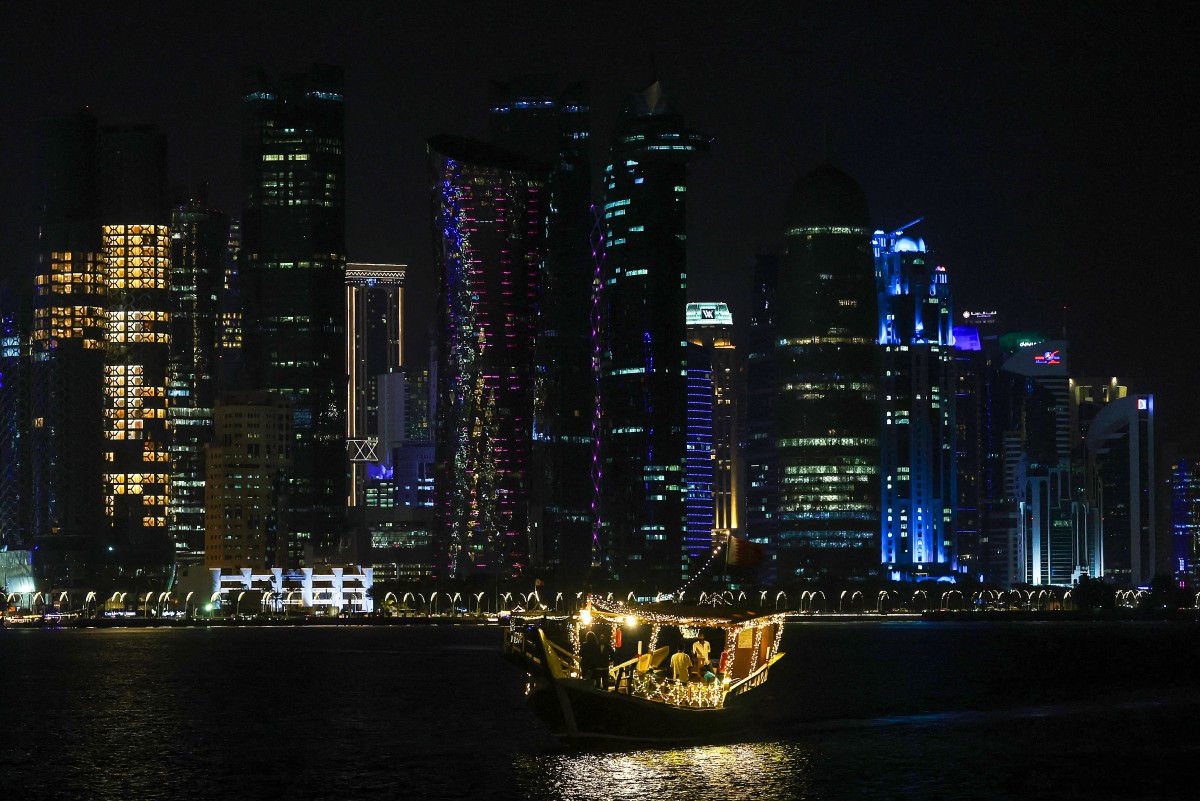 Tourists ride a traditional boat along the Corniche promenade in Doha early on November 8, 2024. (Photo by KARIM JAAFAR / AFP)