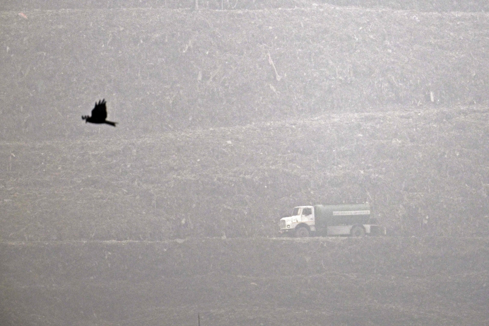  A garbage truck rides across the Ghazipur landfill amid smoggy conditions in New Delhi on November 19, 2024. Photo by Arun SANKAR / AFP