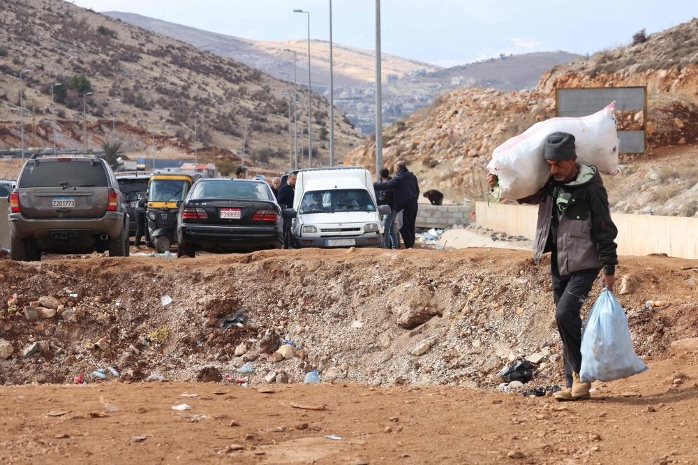 A man fleeing Israeli bombardment in Lebanon crosses a crater, caused by an Israeli strike, in the area of Masnaa, on November 20, 2024. (Photo by Anwar Amro / AFP)