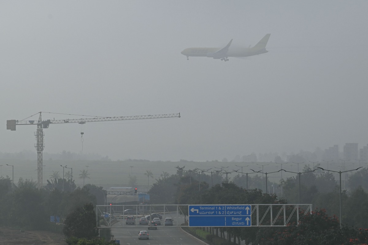 A DHL aircraft prepares to land during a foggy morning at Kempegowda International Airport in Bengaluru on November 22, 2024. (Photo by IDREES MOHAMMED / AFP)