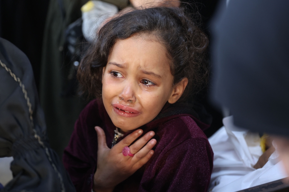 A girl cries as the bodies of victims of an Israeli strike the previous night are brought to at Al-Ahli Arab hospital, also known as the Baptist hospital, in Gaza City on November 22, 2024. (Photo by Omar Al-Qattaa/ AFP)