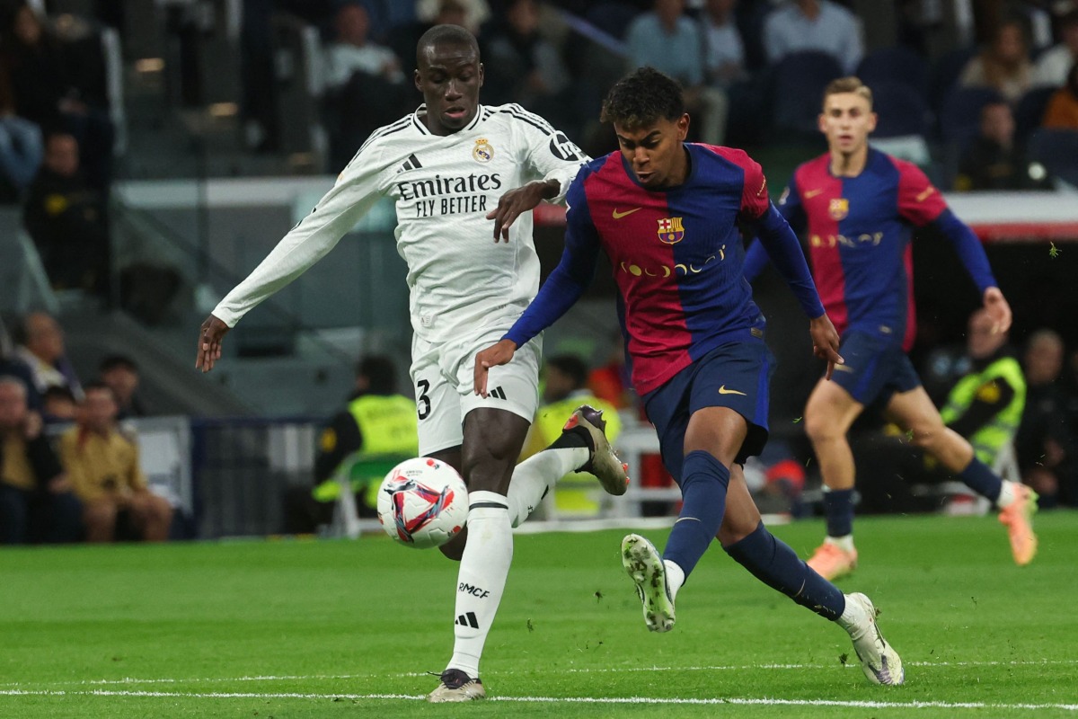 Barcelona's Spanish forward #19 Lamine Yamal (C) is challenged by Real Madrid's German defender #22 Antonio Ruediger during the Spanish league football match between Real Madrid CF and FC Barcelona at the Santiago Bernabeu stadium in Madrid on October 26, 2024. (Photo by Pierre-Philippe MARCOU / AFP)