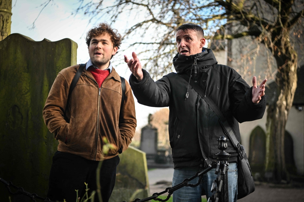 Invisible Cities guide Sonny Murray (R) leads a walking tour with student Arthur Lyhne-Gold, in Cannongate Kirk, Edinburgh, on November 17, 2024. (Photo by Andy Buchanan / AFP)