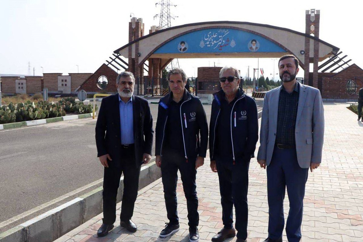 This handout picture provided by the Atomic Energy Organisation of Iran on November 15 2024 shows the organisation's spokesman Behrouz Kamalvandi (L) and Iran's Deputy Foreign Minister Kazem Gharib Abadi (R), posing for a picture with the International Atomic Energy Agency (IAEA) chief Rafael Grossi (2nd-L), in front of the gate of the Fordow nuclear enrichment plant, in Fordow near the city of Qom. Grossi on November 15 toured two Iranian uranium enrichment plants that have been the focus of Western concern, after Tehran said it was ready to address 