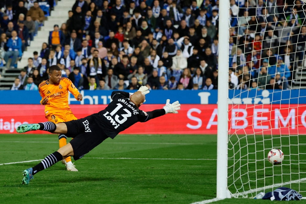 Real Madrid's French forward #09 Kylian Mbappe (left) scores the opening goal during the Spanish league football match between Club Deportivo Leganes SAD and Real Madrid CF at the Estadio Municipal Butarque in Leganes on November 24, 2024. (Photo by Oscar Del Pozo / AFP)