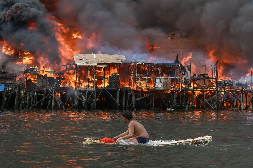  A man watches houses on fire at Tondo in Manila on November 24, 2024. Photo by JAM STA ROSA / AFP