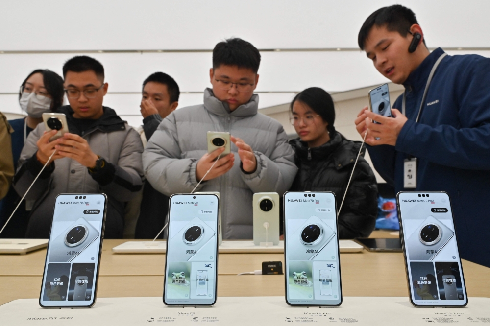 People check Huawei's new Mate 70 mobile phone inside a shop at the Wangfujing shopping area in Beijing on November 26, 2024. (Photo by Adek Berry / AFP)