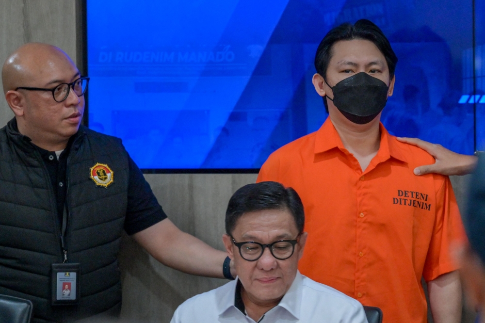 Indonesian immigration officers escort Filipino fugitive Hector Aldwin Liao Pantollana (R) during a press conference in Jakarta on November 26, 2024. Photo by BAY ISMOYO / AFP