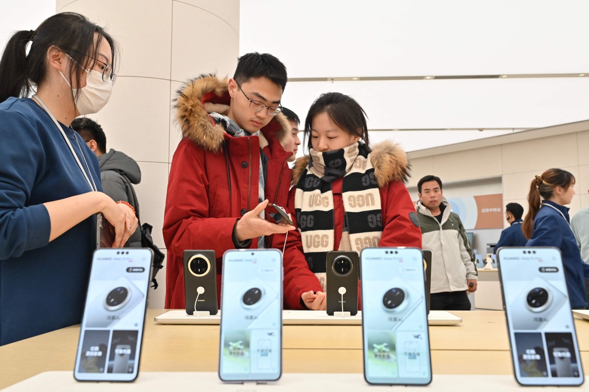 People check Huawei's new Mate 70 mobile phone inside a shop at the Wangfujing shopping area in Beijing on November 26, 2024. (Photo by ADEK BERRY / AFP)
