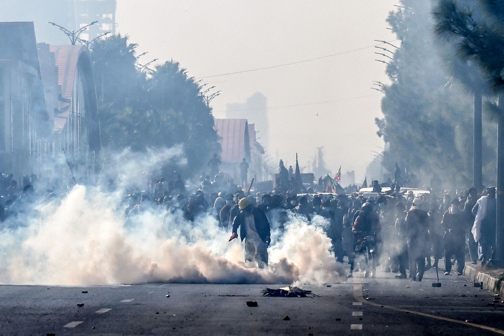 Policemen fire tear gas shells to disperse supporters of the Pakistan Tehreek-e-Insaf (PTI) party during a protest demanding the release of former prime minister Imran Khan, at the Red Zone area in Islamabad on November 26, 2024. (Photo by Aamir Qureshi / AFP)