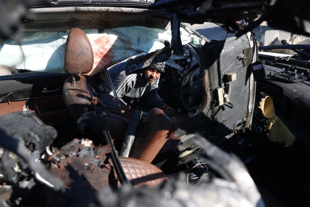 A man checks a car hit by an Israeli strike in Khan Yunis in the southern Gaza Strip on November 30, 2024, in which five people were targeted, including three World Central Kitchen (WCK) workers, according to a report by the civil defence in the Palestinian territory. Photo by BASHAR TALEB / AFP.