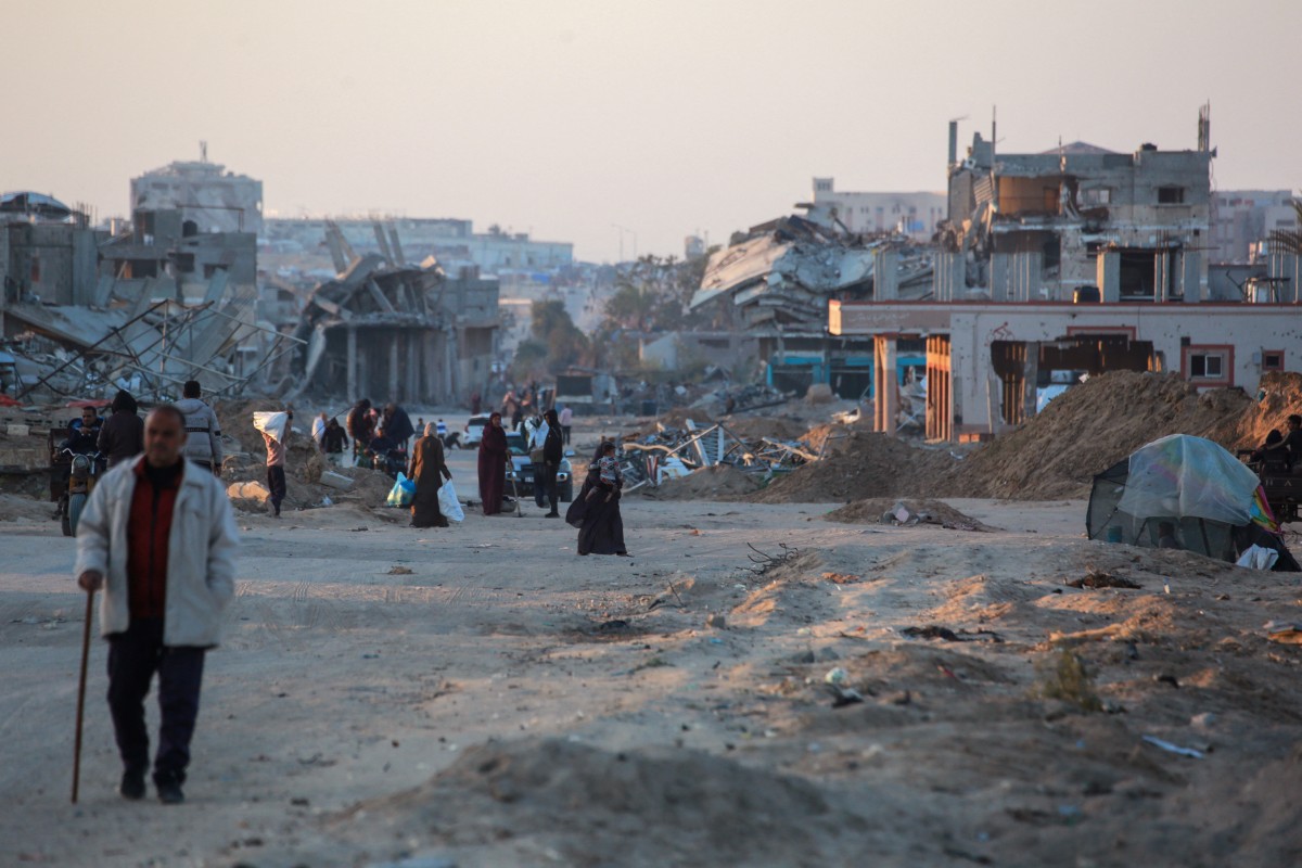 Palestinians walk in a devastated neighbourhood due to Israeli strikes in the southern Gaza Strip's city of Khan Yunis on December 2, 2024. Photo by Bashar TALEB / AFP.