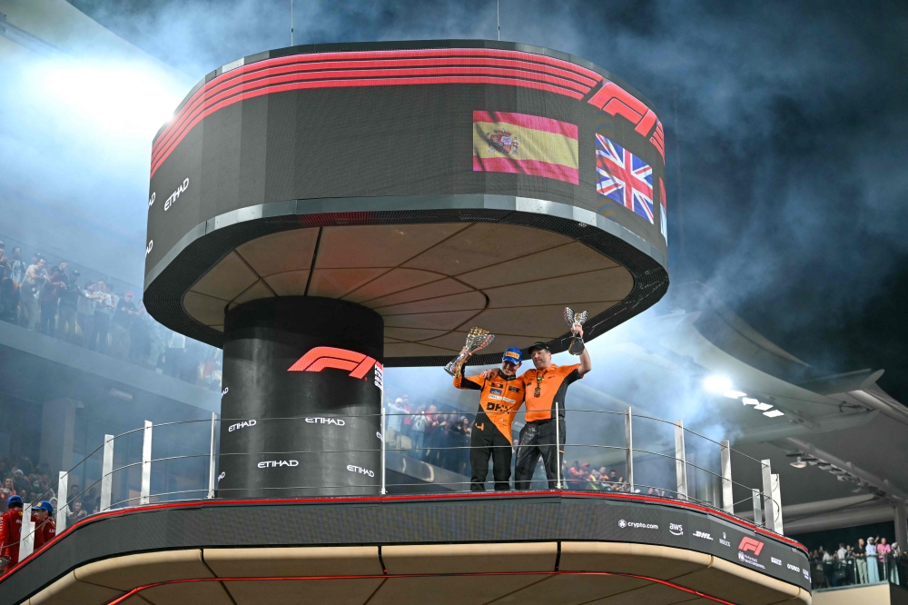 McLaren's British driver Lando Norris (L) and McLaren's US principal Zak Brown celebrate on the podium after winning the constructors championship at the end of the Abu Dhabi Formula One Grand Prix at the Yas Marina Circuit in Abu Dhabi on December 8, 2024. (Photo by Andrej ISAKOVIC / AFP)