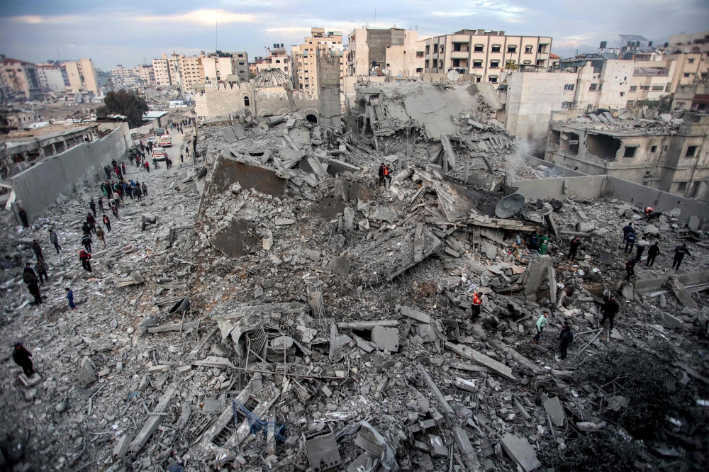 People and first responders inspect the rubble of a collapsed residential building that was hit by Israeli bombardment in the Saraya area in al-Rimal,  central Gaza on January 4, 2025. (Photo by Omar Al-Qattaa / AFP)
